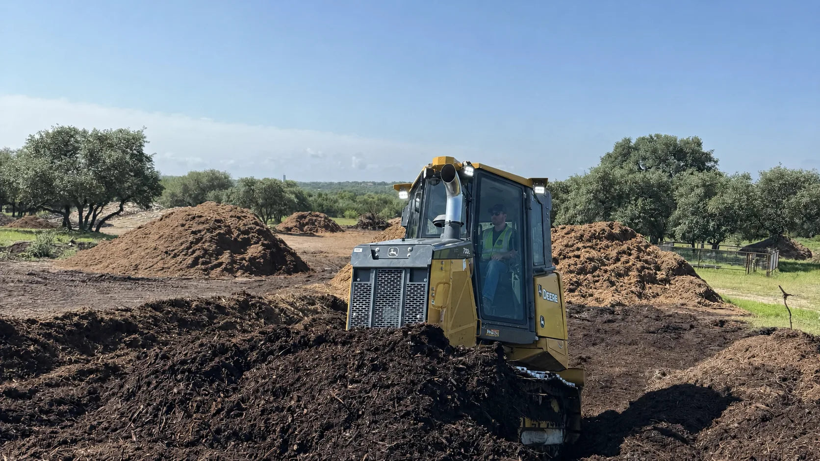 Mulch yard loader working beside brush and mulch piles at Burnet Brush Depot in Burnet Texas